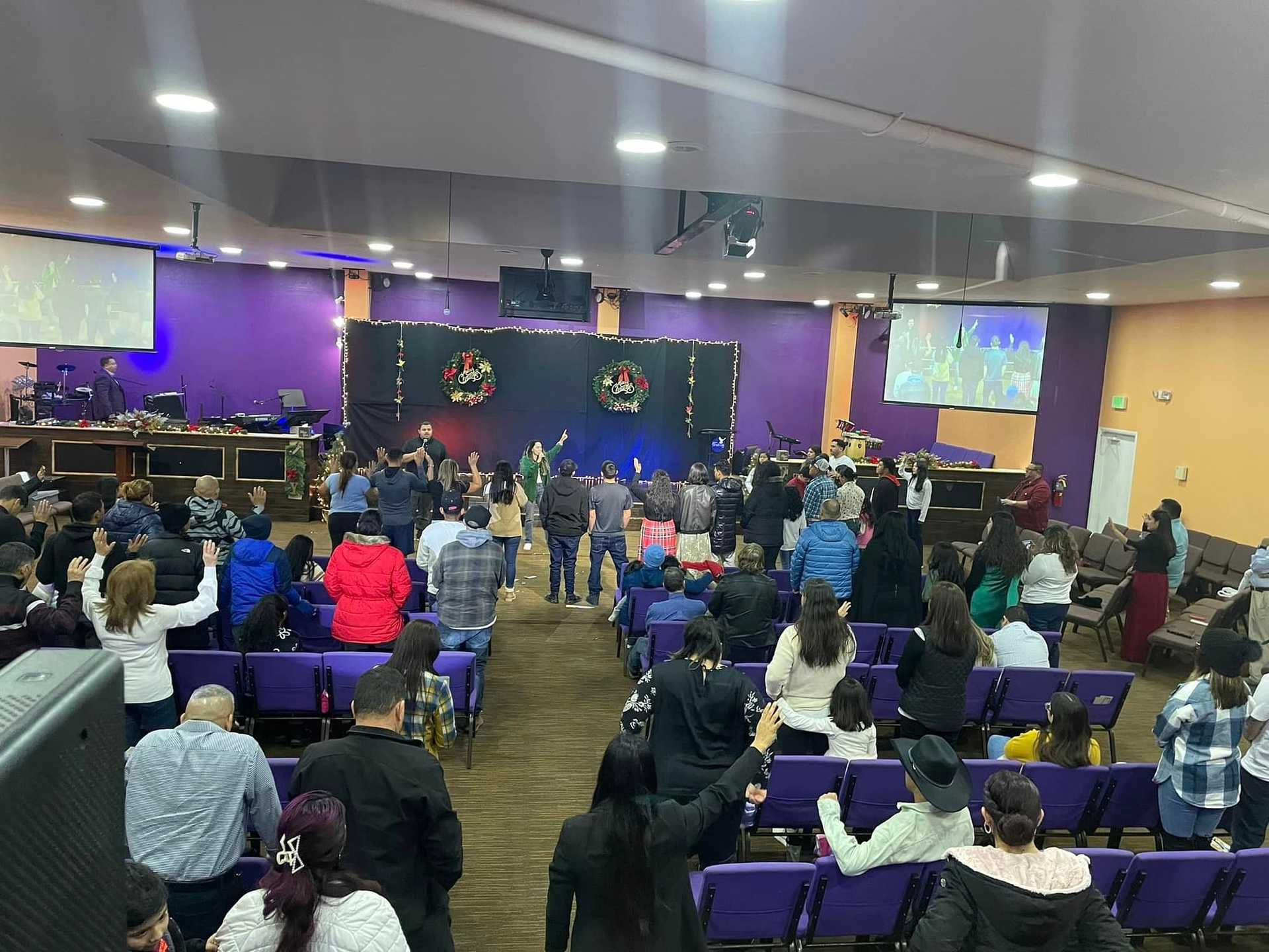 Congregation participating in a Christmas event in a decorated church auditorium.