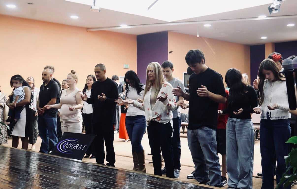 People standing in a room, appearing to be engaged in a group activity or exercise.